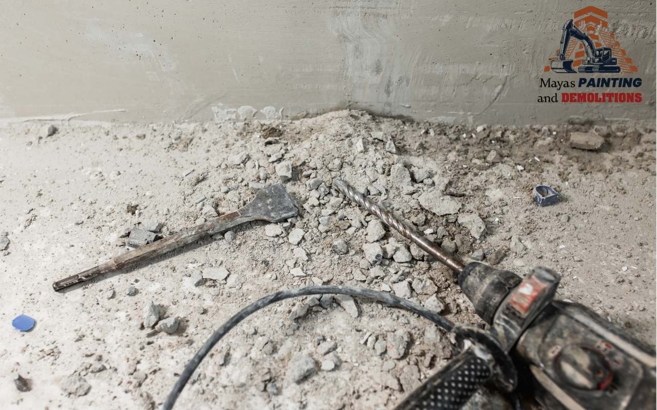 A worker using a rotary hammer to drill into concrete.