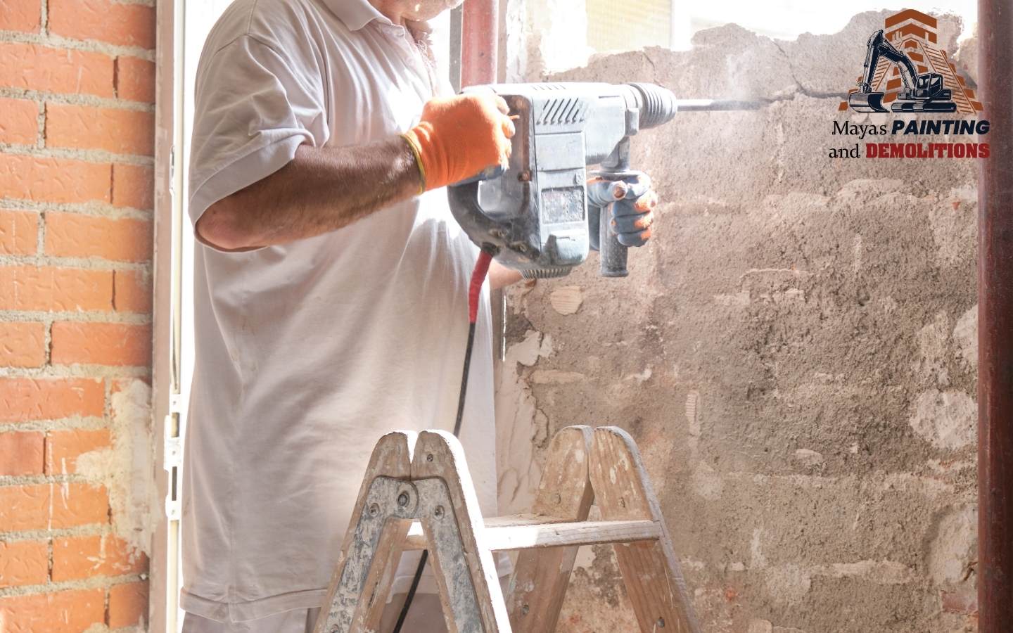 A construction worker wearing protective gear while operating a demolition hammer.